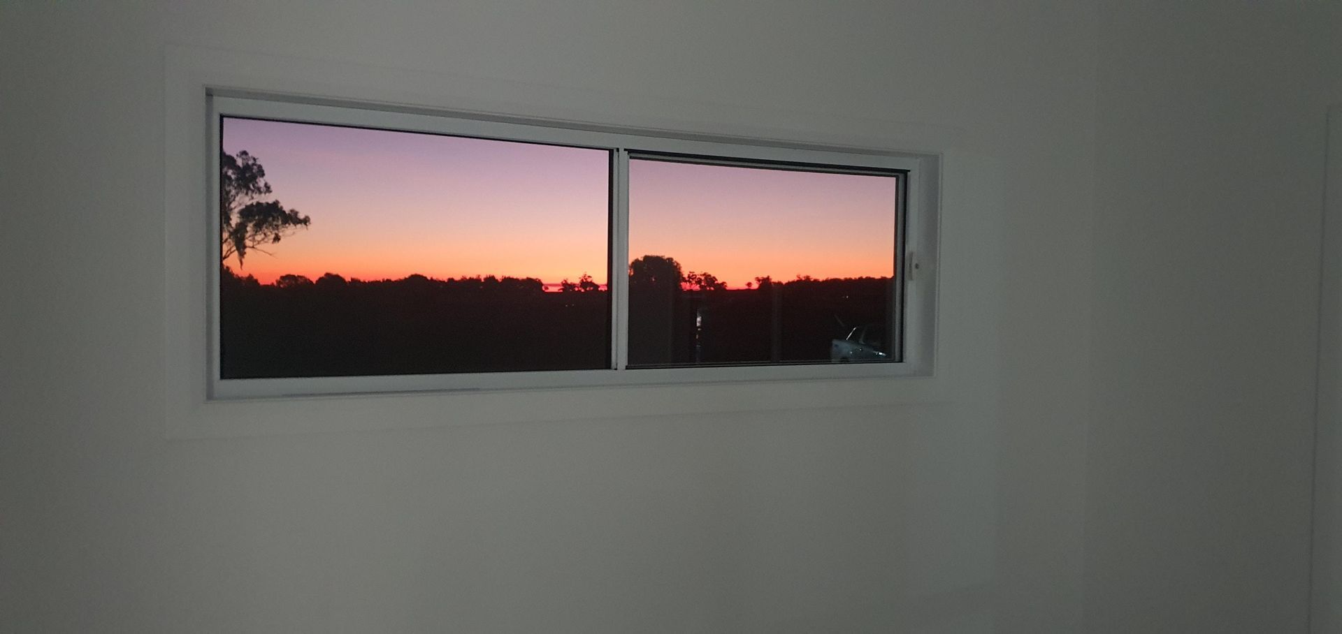 A Sunset is Visible Through a Window in a Room — Kareela Constructions In Tamworth, NSW