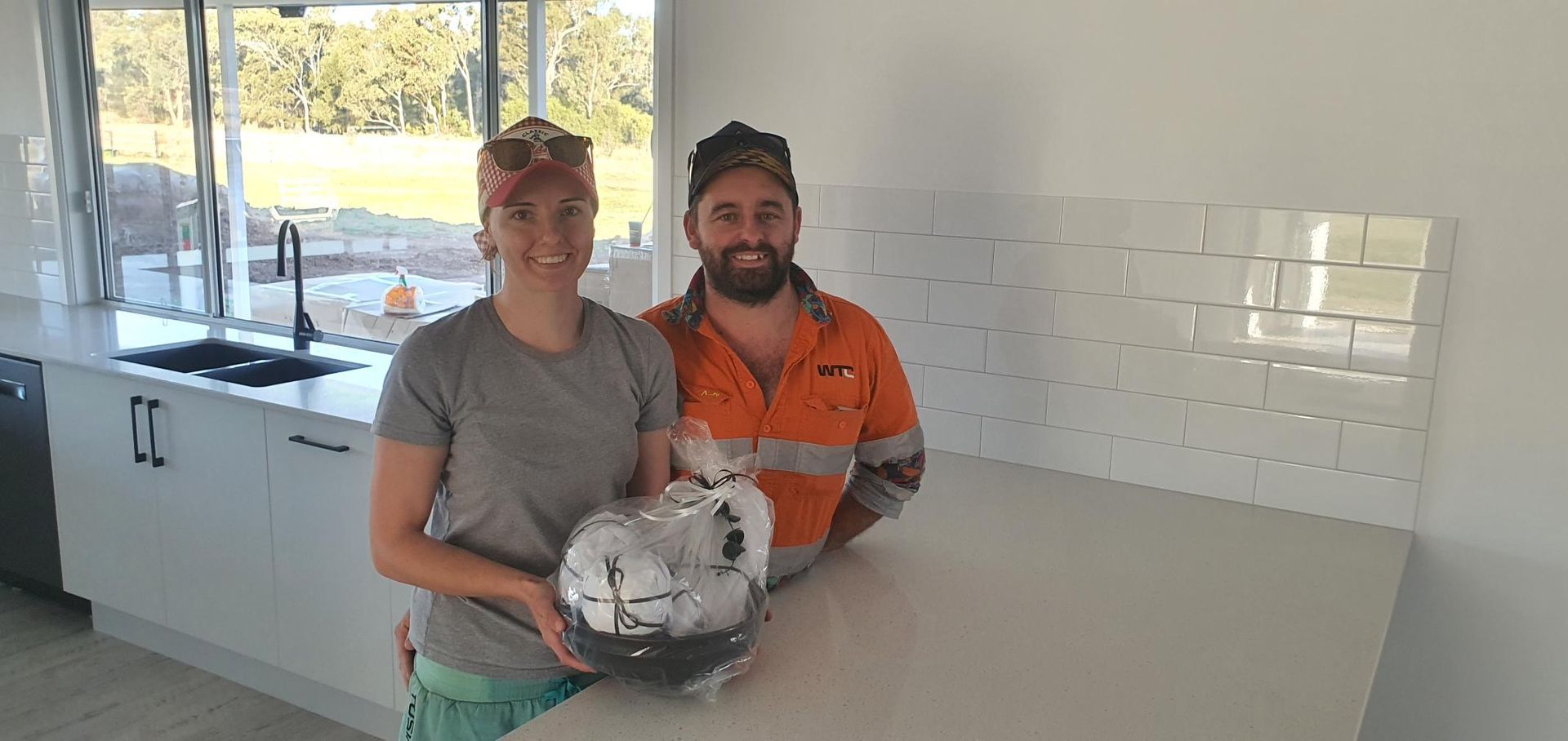 A Man and a Woman Are Standing in a Kitchen Holding a Soccer Ball — Kareela Constructions In Tamworth, NSW