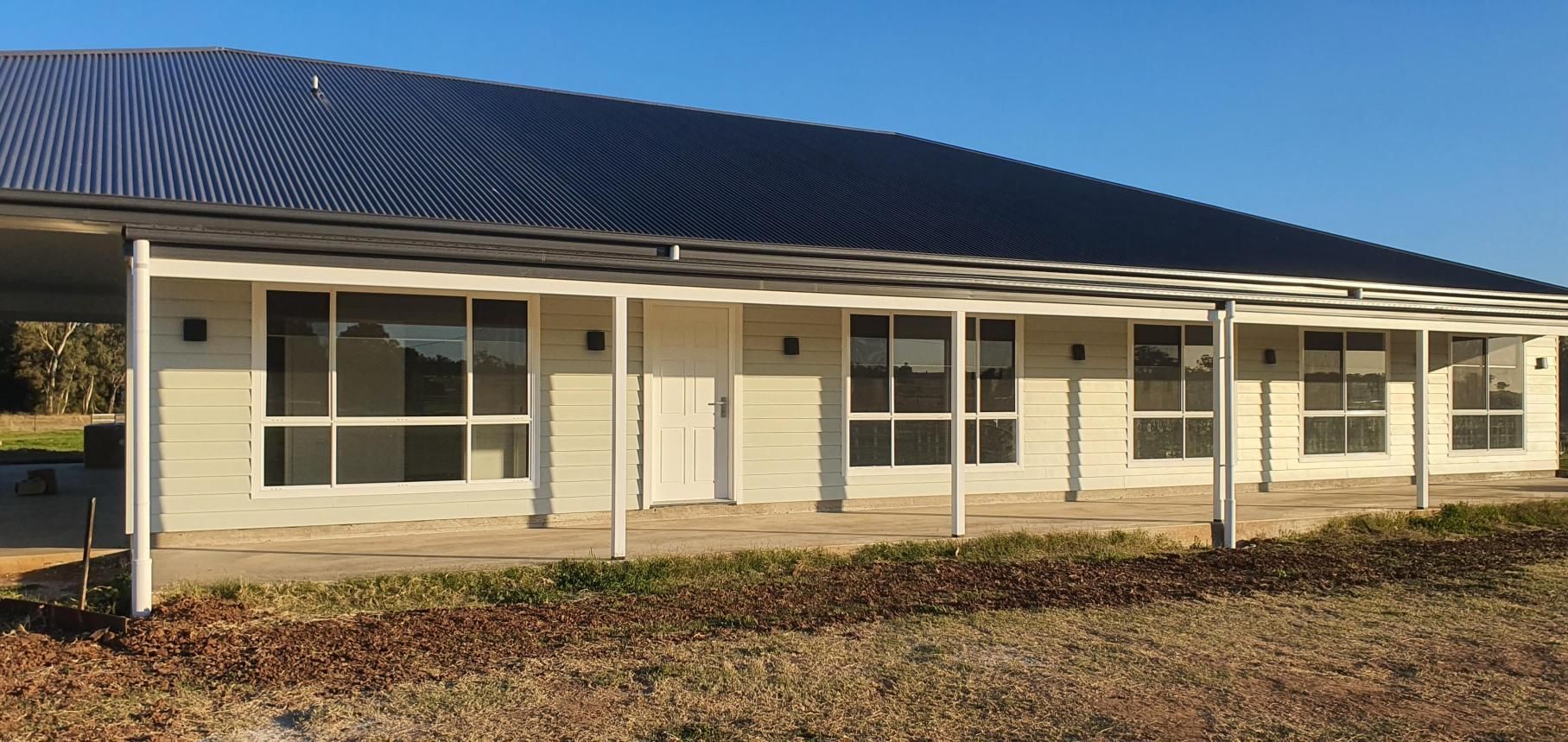 A Large White House With a Porch and a Blue Sky in the Background — Kareela Constructions In Tamworth, NSW