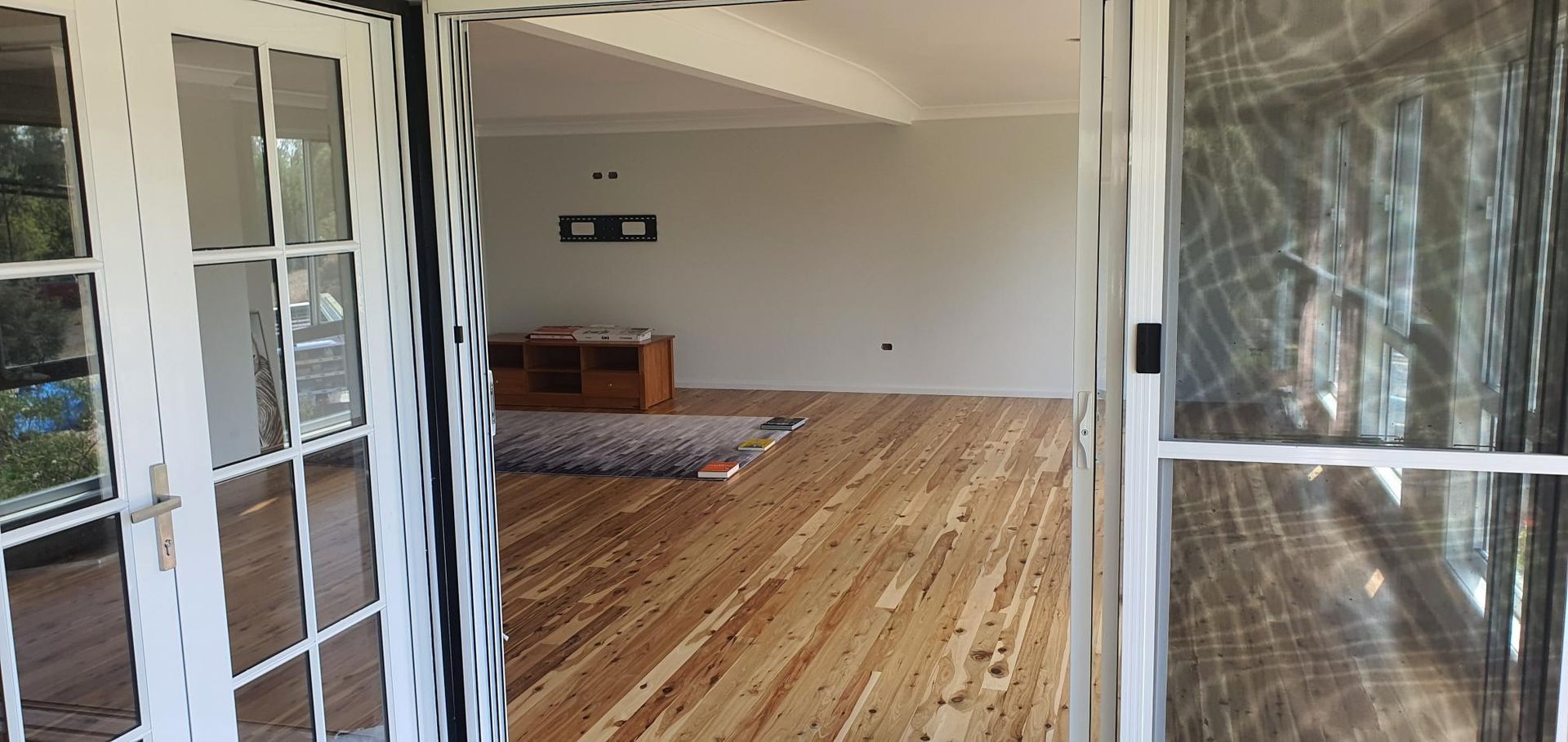 A Living Room With Hardwood Floors and Sliding Glass Doors — Kareela Constructions In Tamworth, NSW