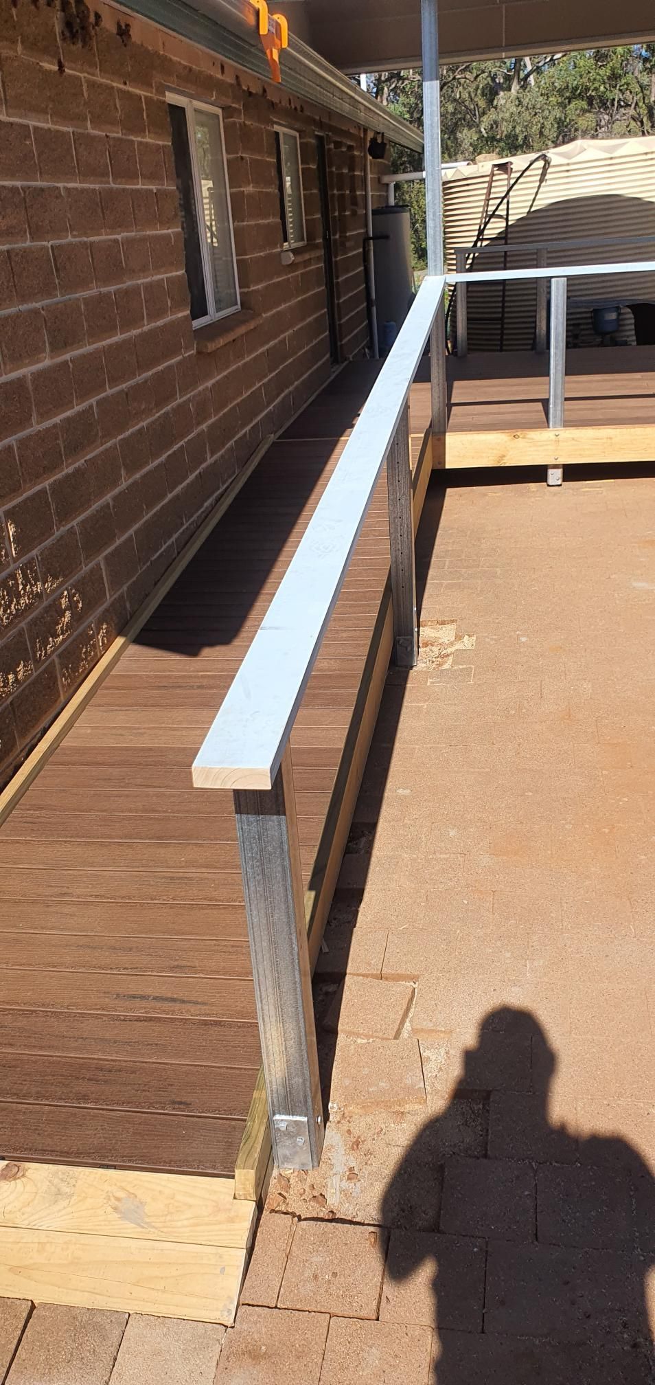 A Shadow of a Person is Cast on a Wooden Deck Next to a House — Kareela Constructions In Tamworth, NSW