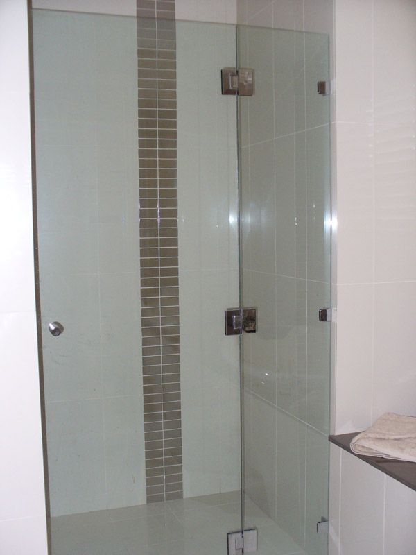 A Bathroom With a Glass Shower Door and a Tiled Wall — Kareela Constructions In Tamworth, NSW