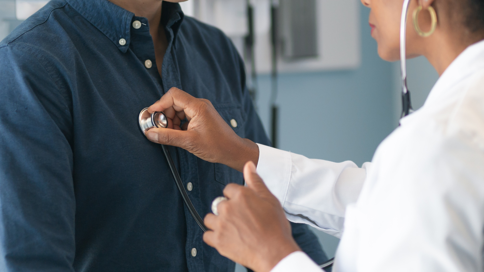 Doctor using a stethoscope to examine a patient’s chest in a clinic