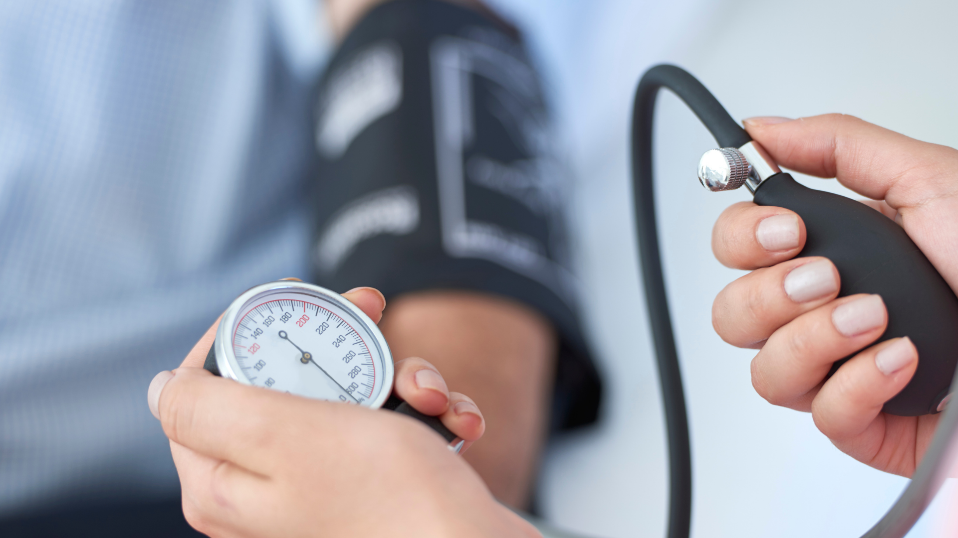 Person measuring blood pressure with a cuff and gauge in a clinical setting