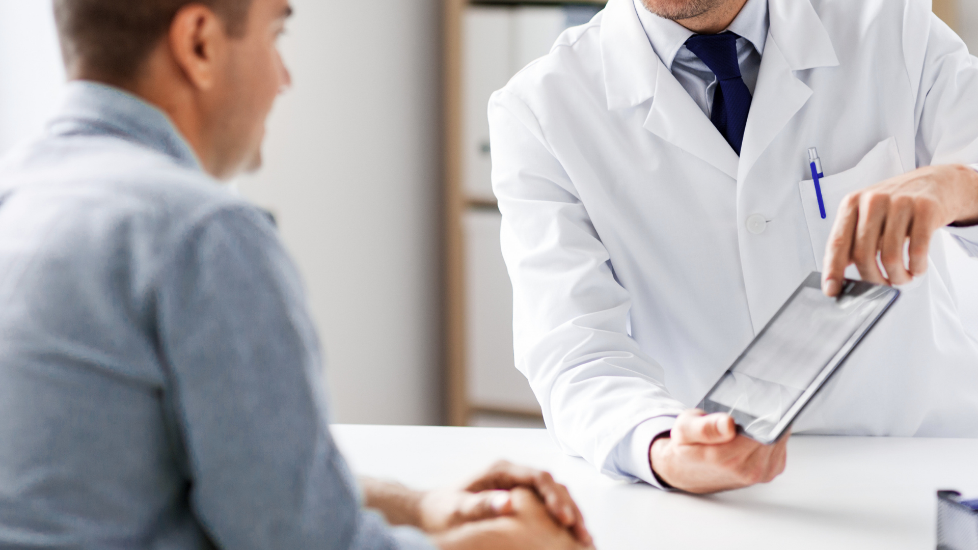 Doctor showing a tablet to a seated patient in a bright clinic office