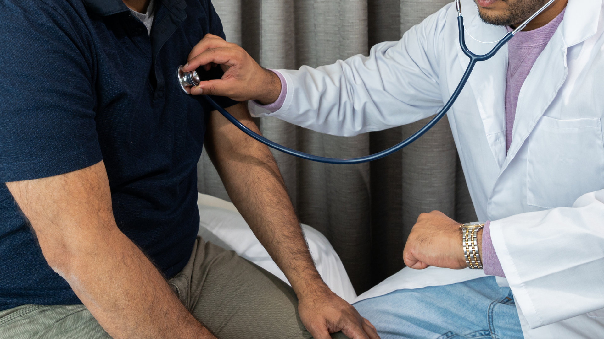 Doctor using a stethoscope to examine a patient’s arm in a clinic