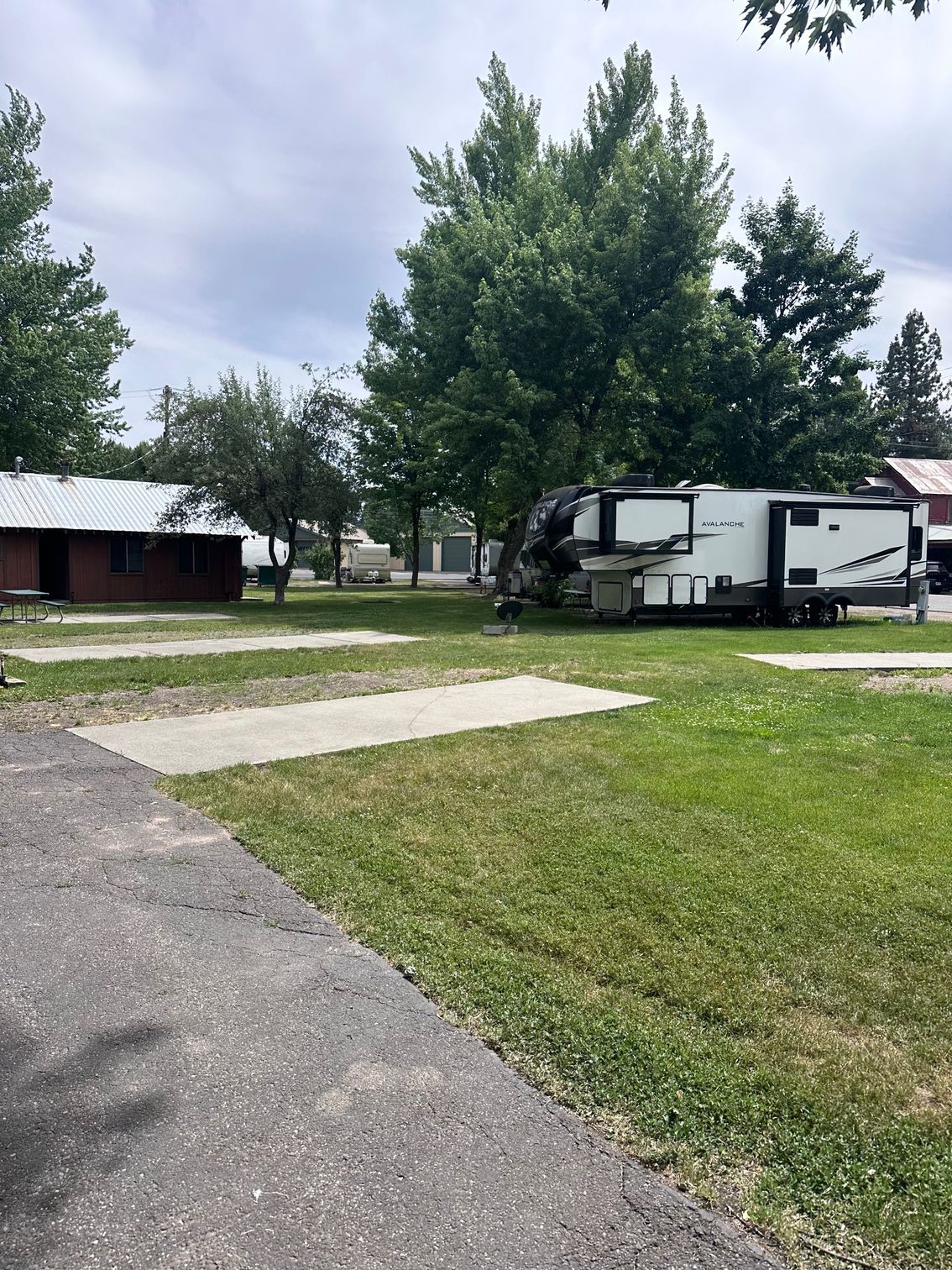 A rv is parked in a grassy field next to a house.