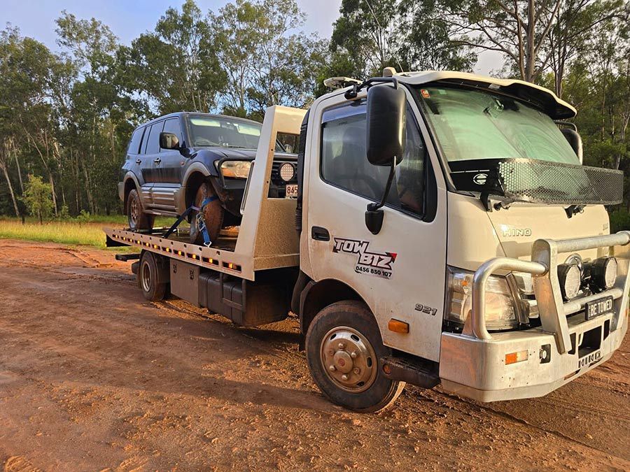 A Tow Truck is Carrying Two Cars on a Dirt Road — Tow Biz in Park Avenue, QLD