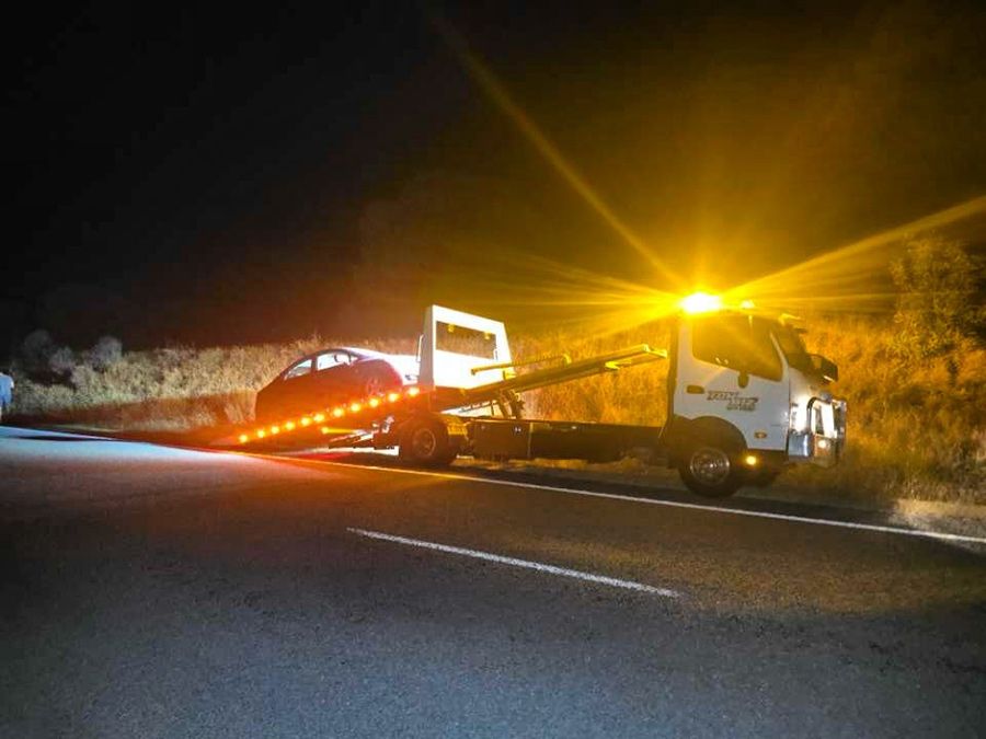 A Tow Truck is Towing a Car Down a Road at Night — Tow Biz in Park Avenue, QLD