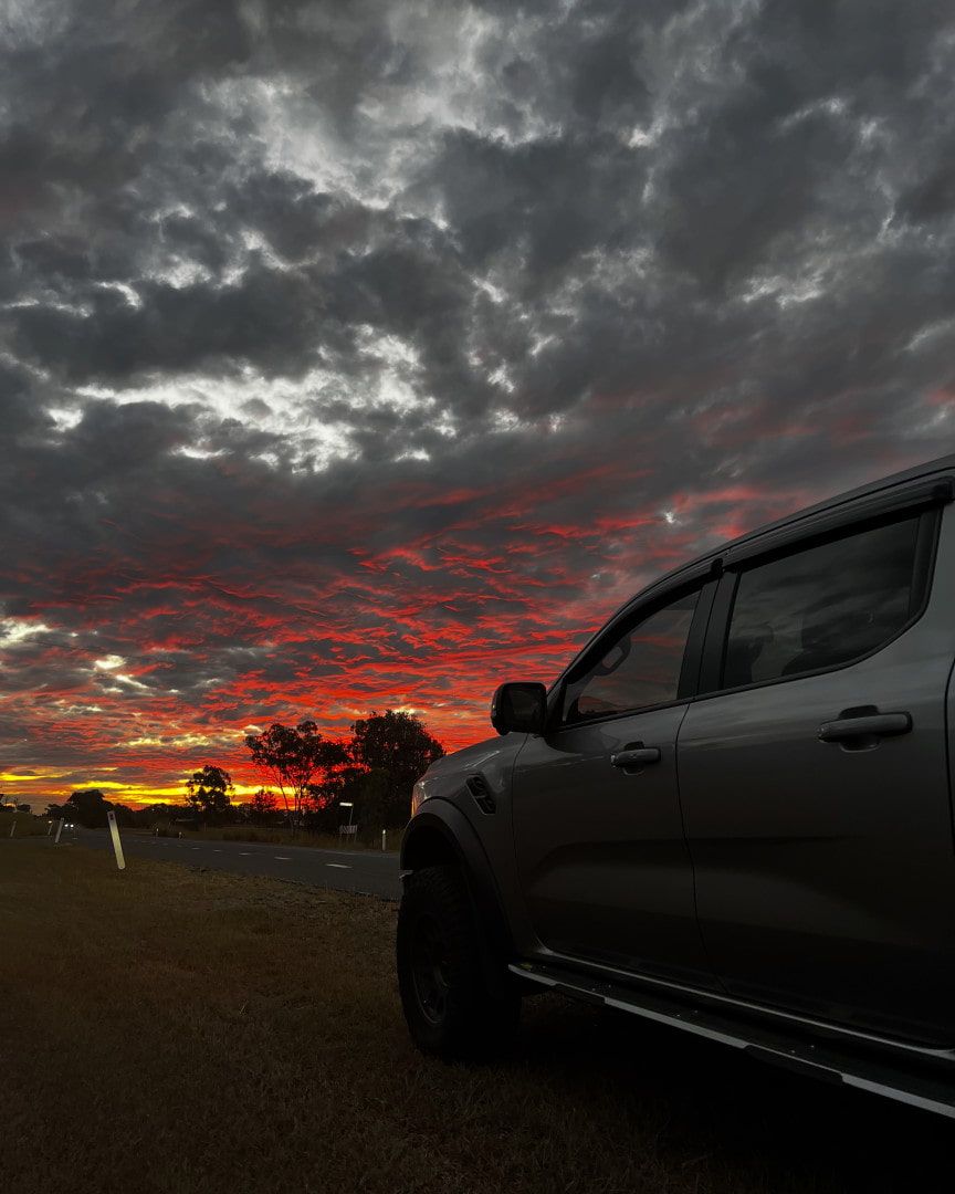 A Car is Parked in a Field With a Sunset in the Background — Tow Biz in Biloela, QLD
