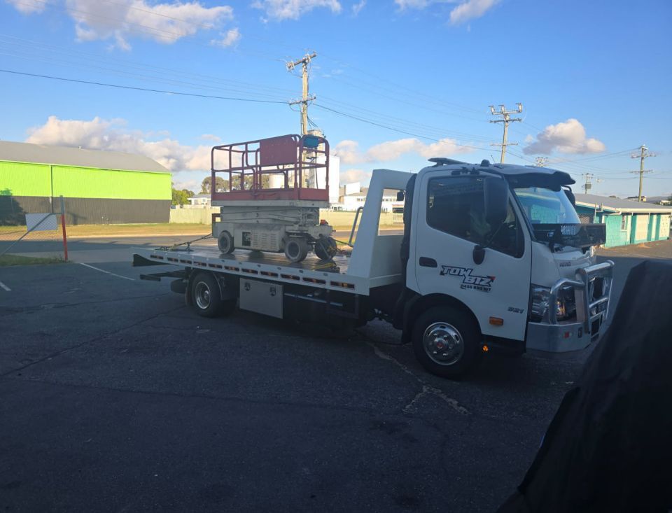 A Tow Truck is Carrying a Scissor Lift on the Back of It — Tow Biz in Emu Park, QLD