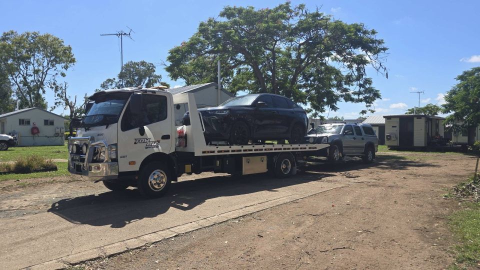 A Tow Truck is Towing a Car Down a Dirt Road — Tow Biz in Emu Park, QLD