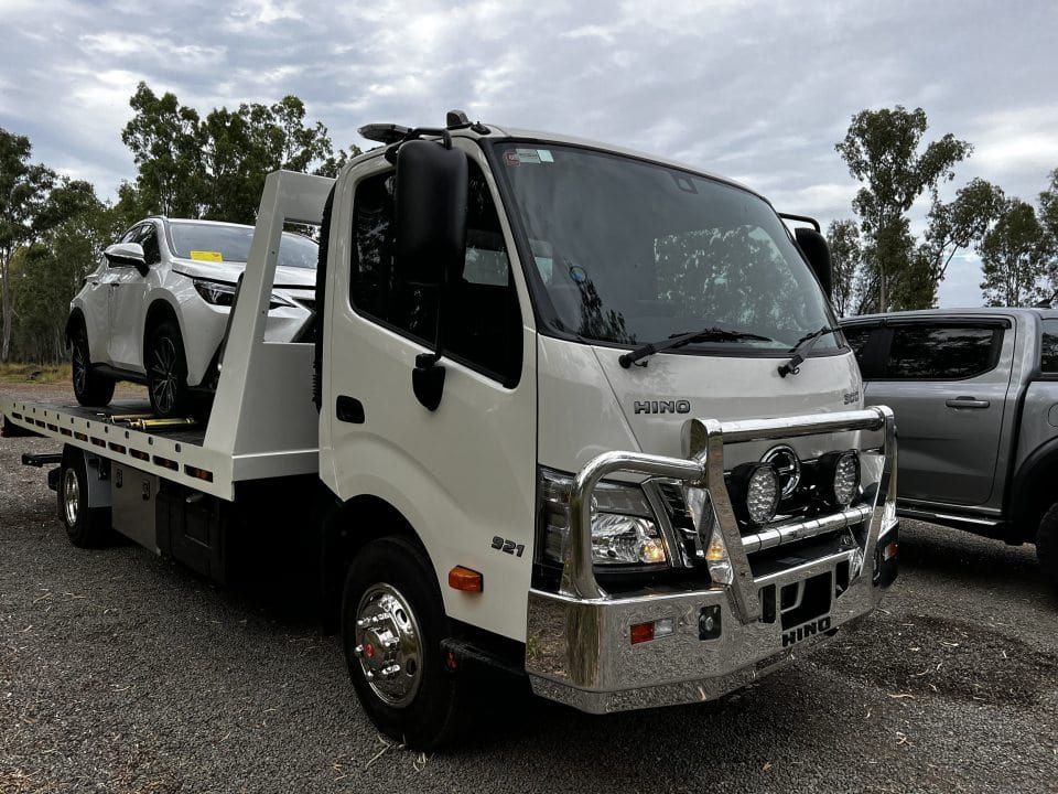 A Tow Truck With a Car on the Back is Parked in a Gravel Lot — Tow Biz in Emu Park, QLD