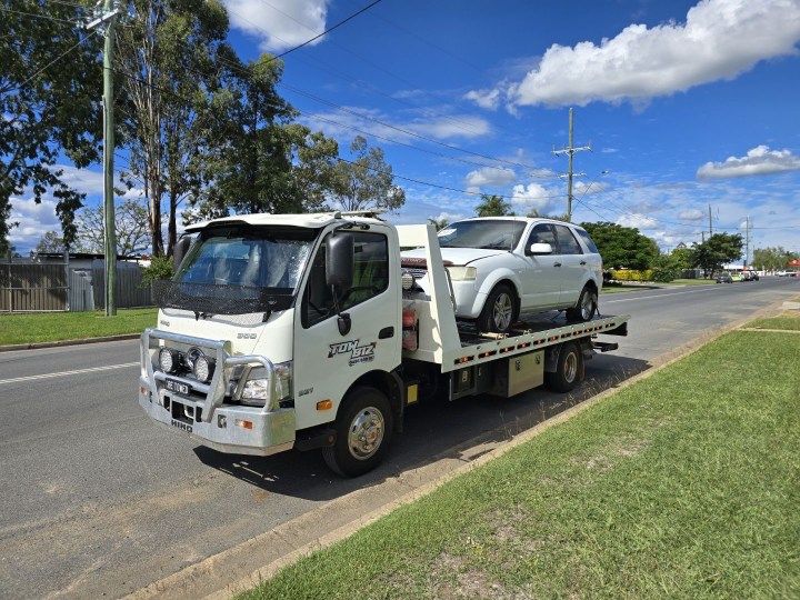 A Tow Truck With a Car on the Back is Parked on the Side of the Road — Tow Biz in Park Avenue, QLD