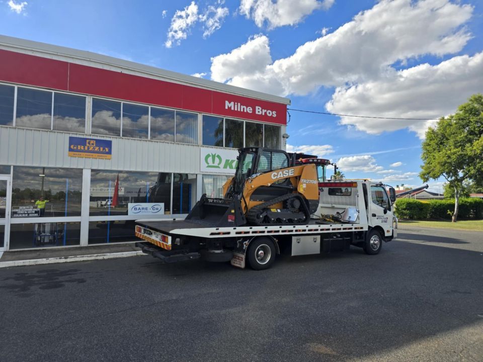 A Tow Truck With a Tractor on the Back is Parked in Front of a Building — Tow Biz in Park Avenue, QLD