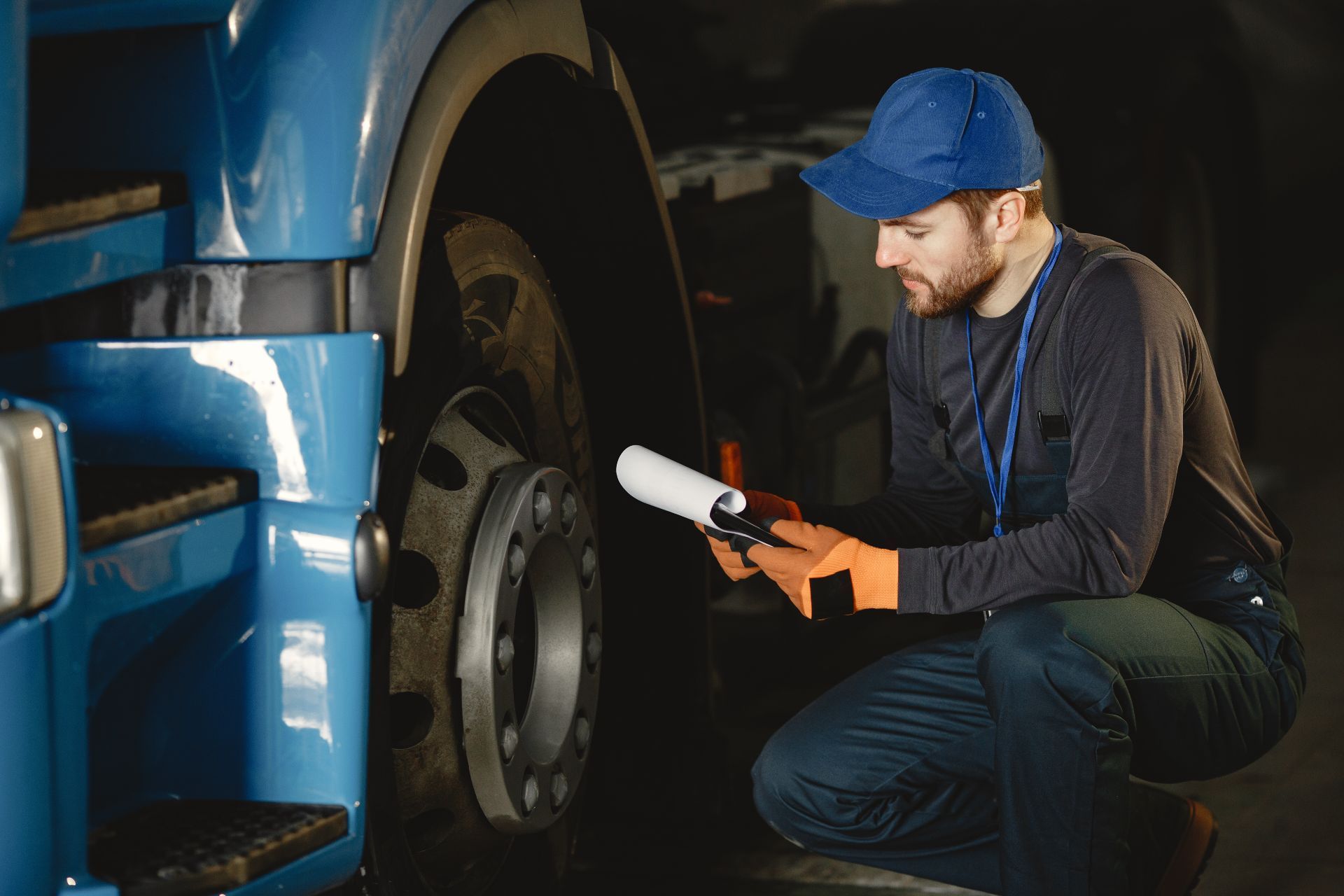 Mechanic inspecting a truck wheel with a flashlight in a garage.