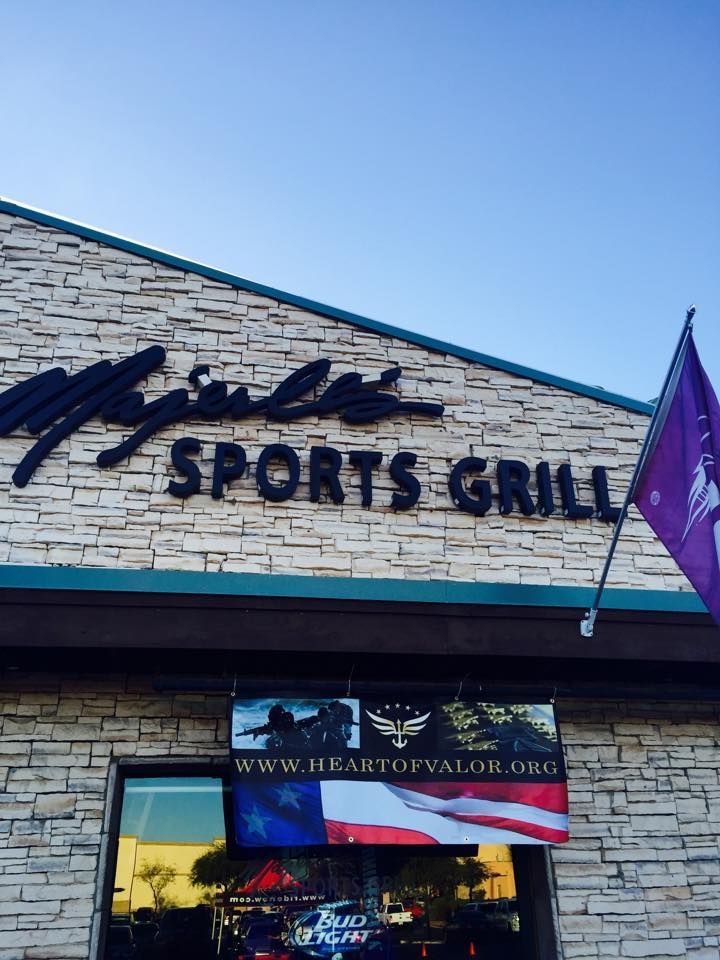 The exterior of Mjule's Sports Grill with a stone facade and a banner for heartofvalor.org featuring an American flag.