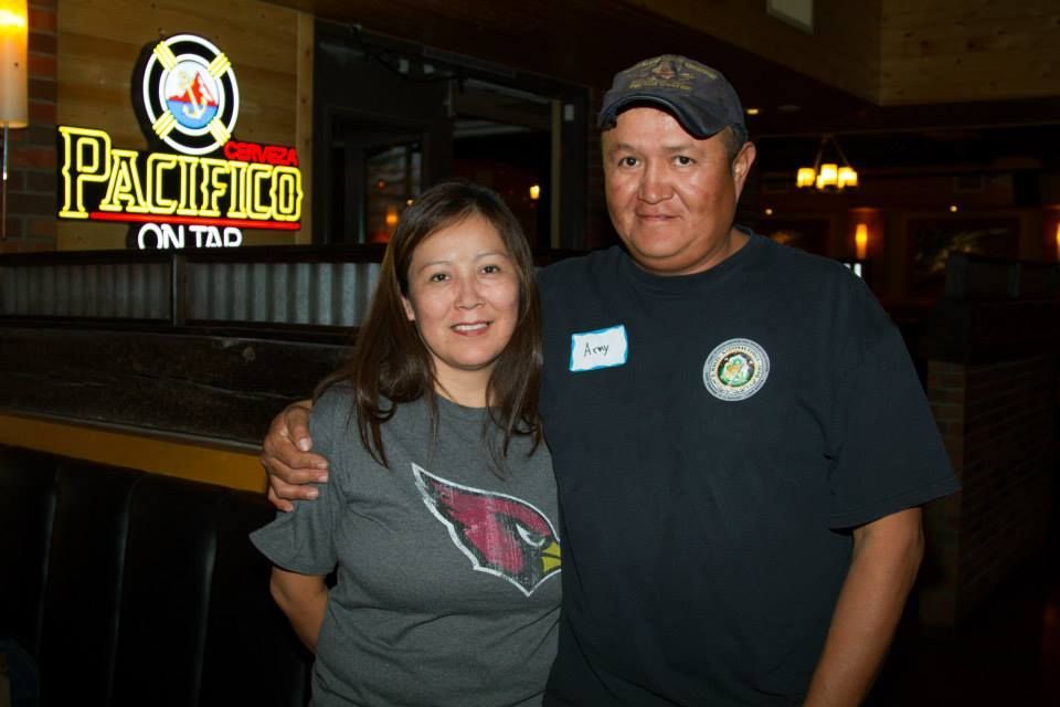 A man and woman smiling together inside a restaurant with a Pacifico neon sign in the background.