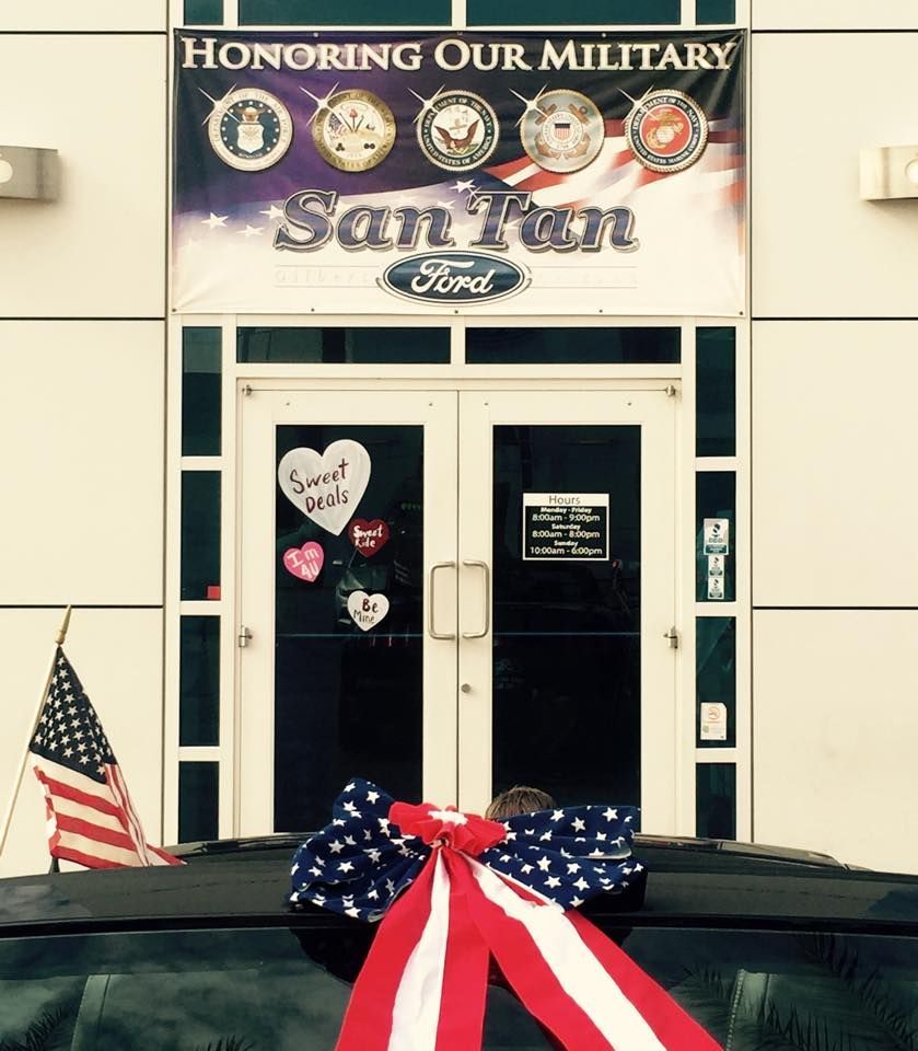 San Tan Ford storefront with a military appreciation banner, American flag, and heart decorations on the glass doors.