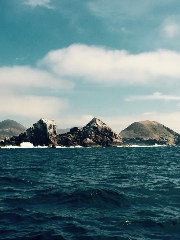 Rocky islands in a deep blue ocean under a partly cloudy sky.