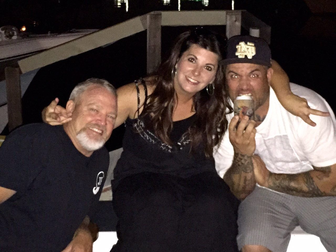 Three people pose for a photo at night, with one person holding an ice cream cone near their mouth.