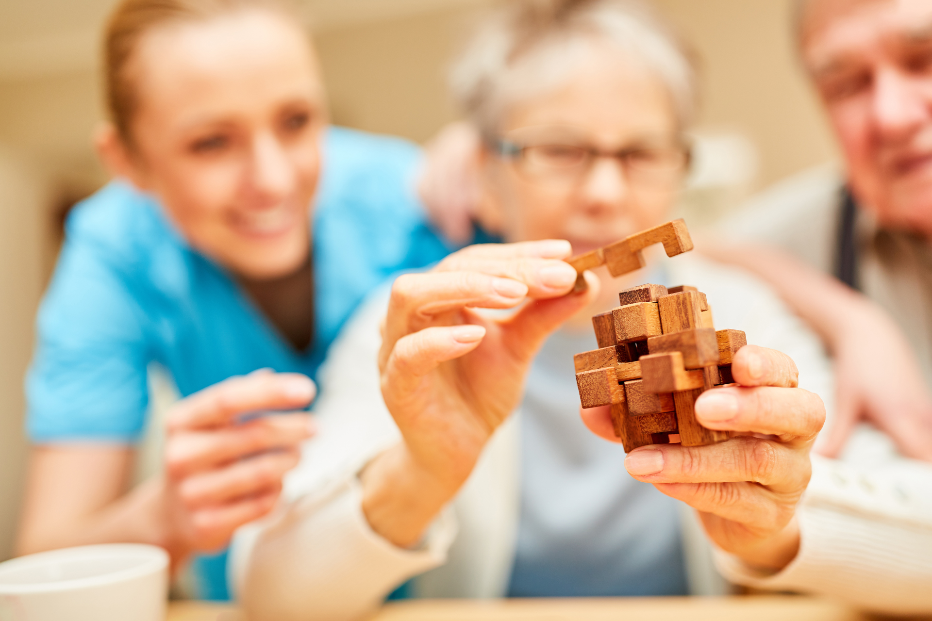 People assembling a wooden puzzle at a table, with focused hands and blurred faces in the background
