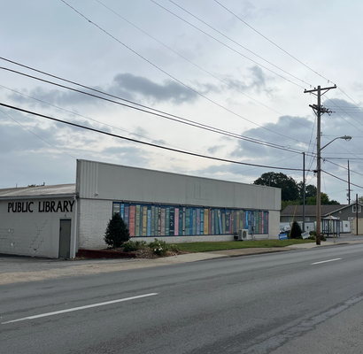 Image of the side of the Madisonville Public Library with a mural showing a bookshelf. 