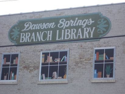 Click the image for contact information Image of the side of the Dawson Springs Branch Library with a mural showing a bookshelf through windows.