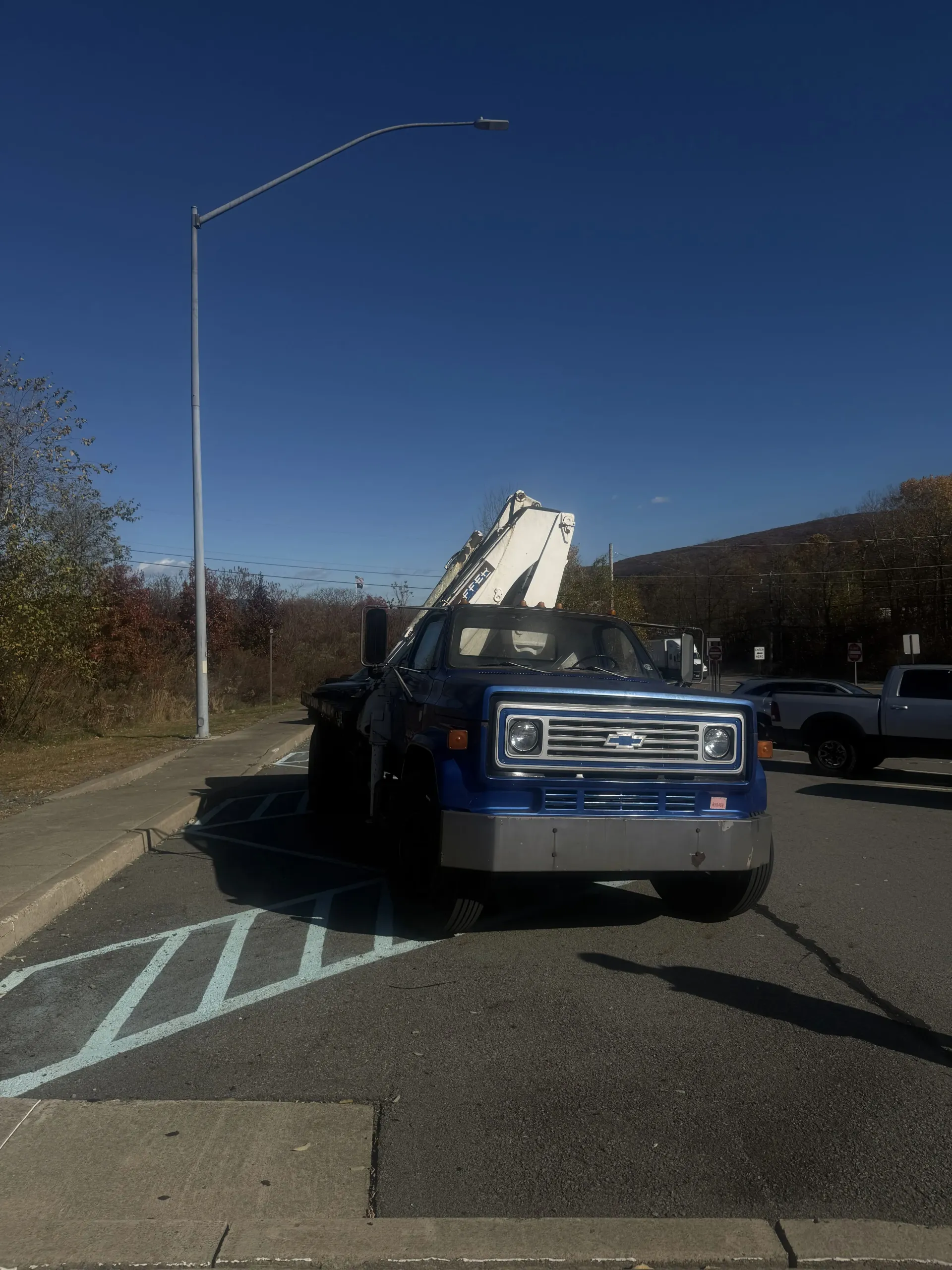 Tow truck with raised boom parked on a road under a clear blue sky