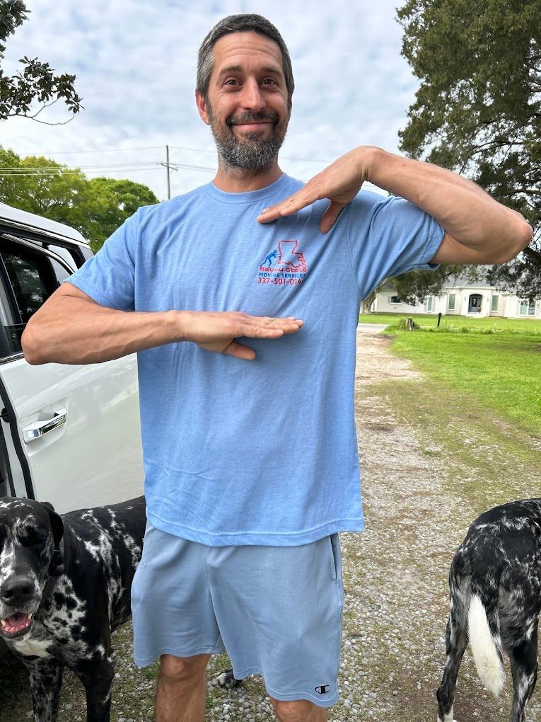A man wearing a blue t-shirt and shorts is standing next to two dogs.