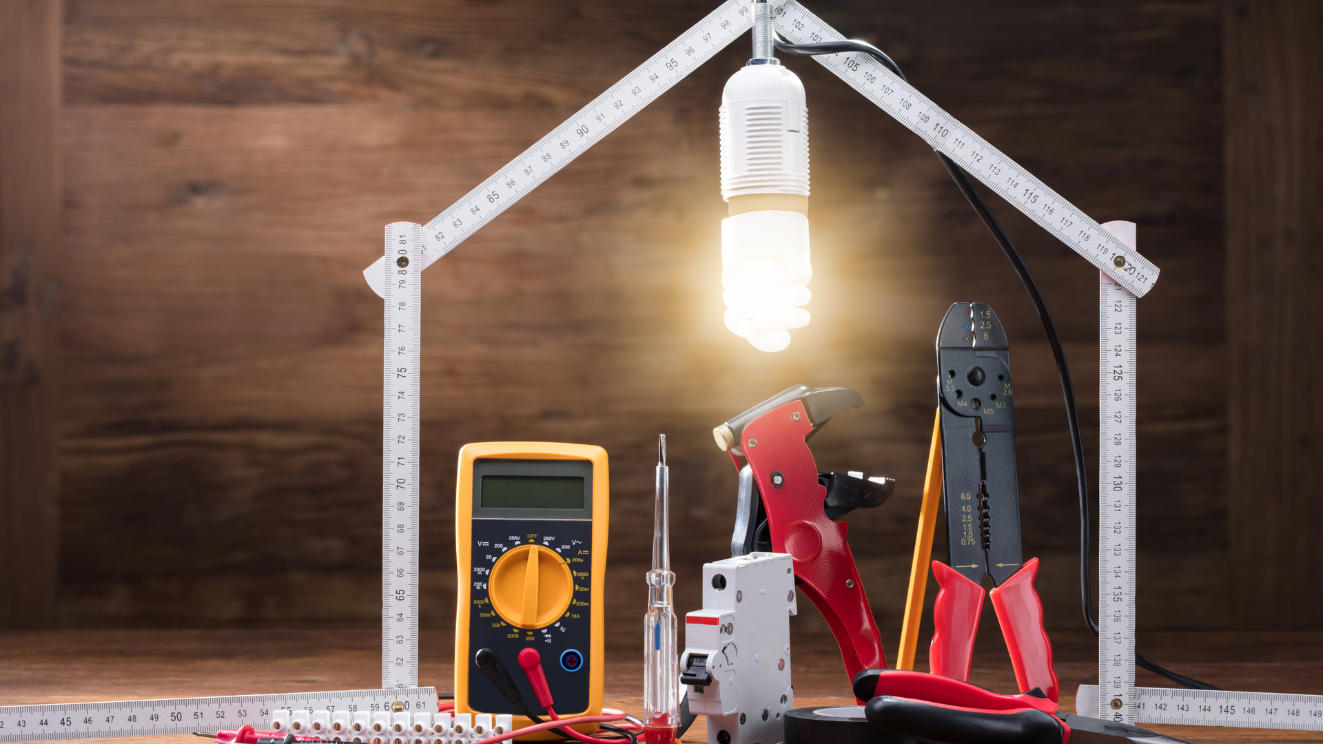 A light bulb is hanging from the roof of a house made out of electrical tools.