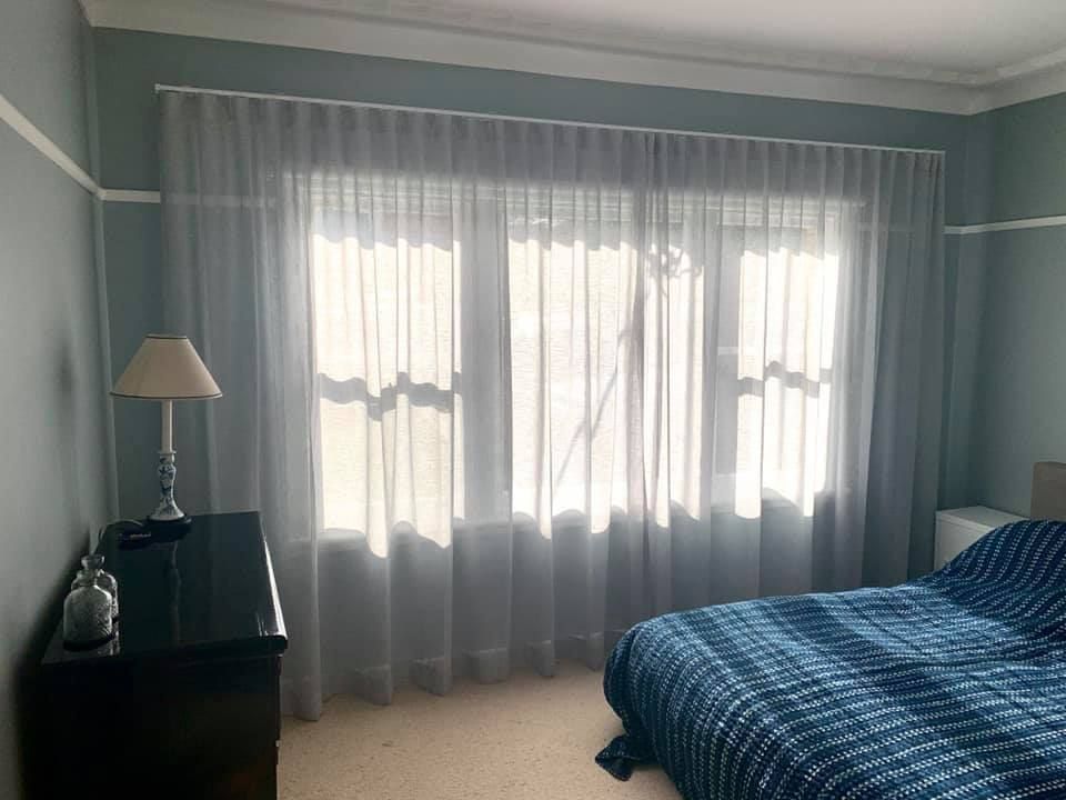 A Bedroom With Sheer Curtains Over a Window — Glenn Koek - Shutters - Curtains - Blinds in West Wollongong, NSW