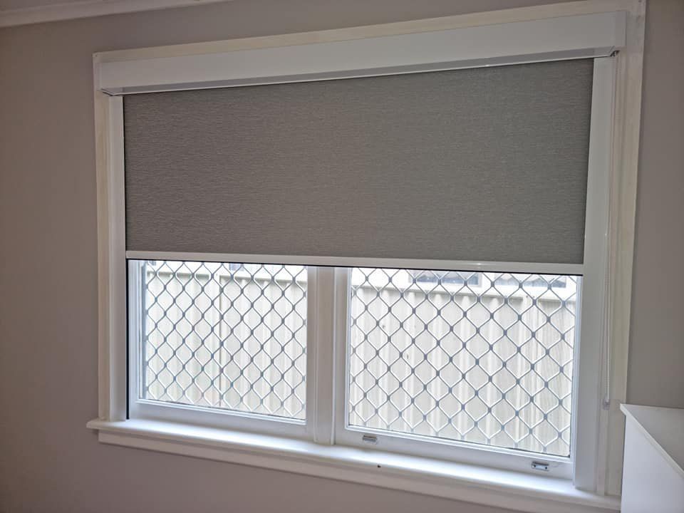 A Window With a Closed Gray Roller Blind — Glenn Koek - Shutters - Curtains - Blinds in Sutherland Shire, NSW