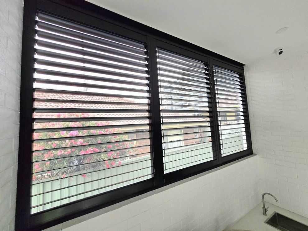 Black-framed window with closed horizontal blinds — Glenn Koek - Shutters - Curtains - Blinds in West Wollongong, NSW