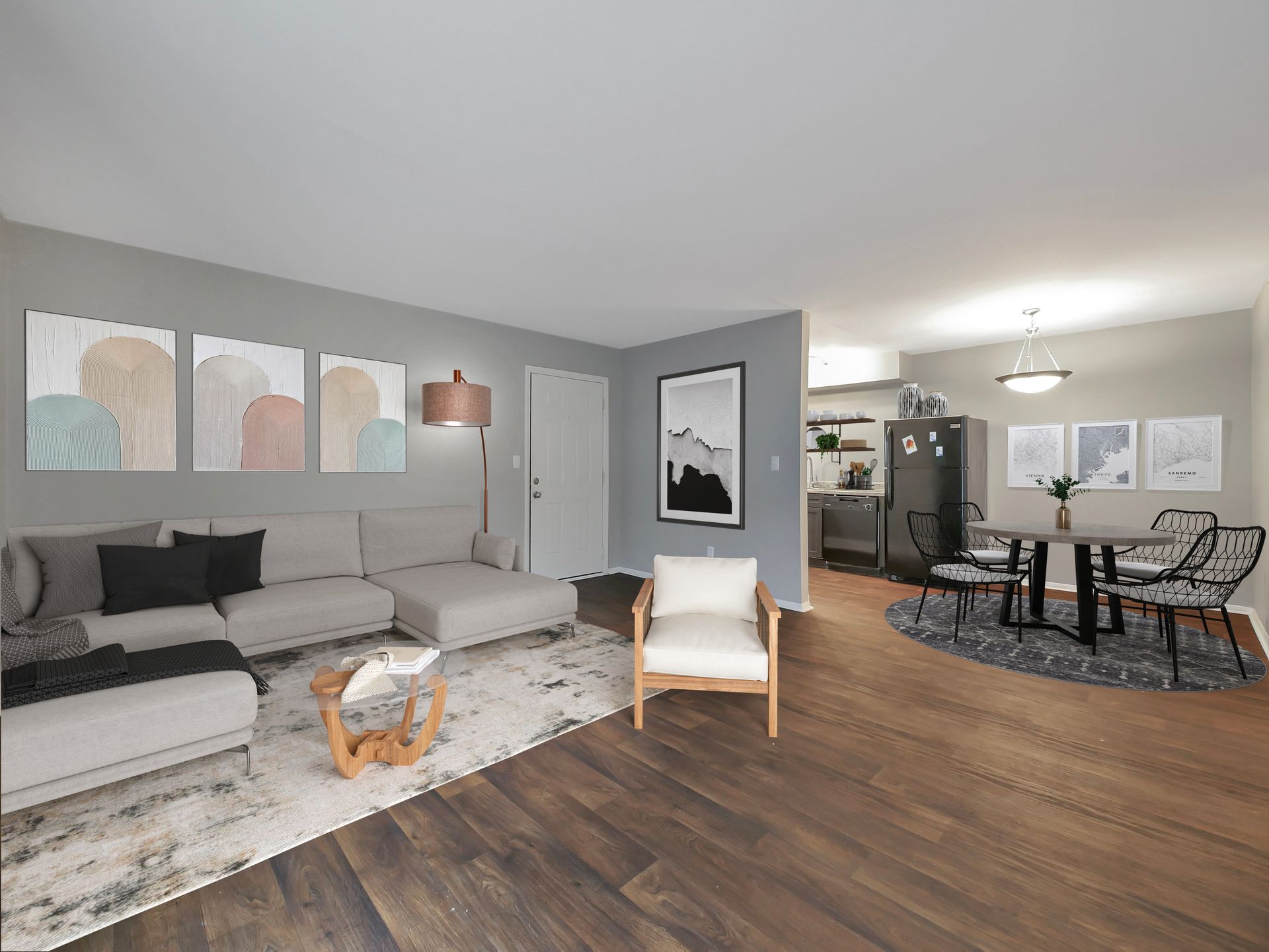 A modern, open-concept apartment with a gray living room, white sofa, area rug, and an adjacent dining area with a table.