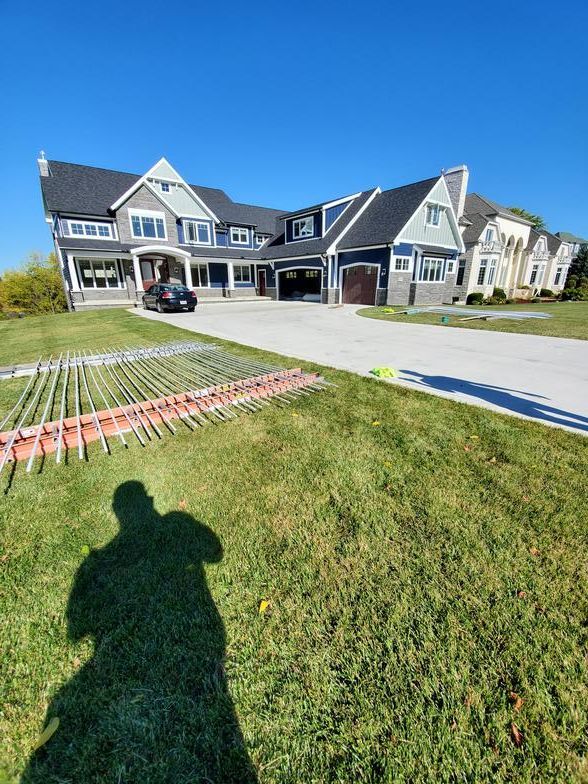 A shadow of a person is cast on the grass in front of a large house.