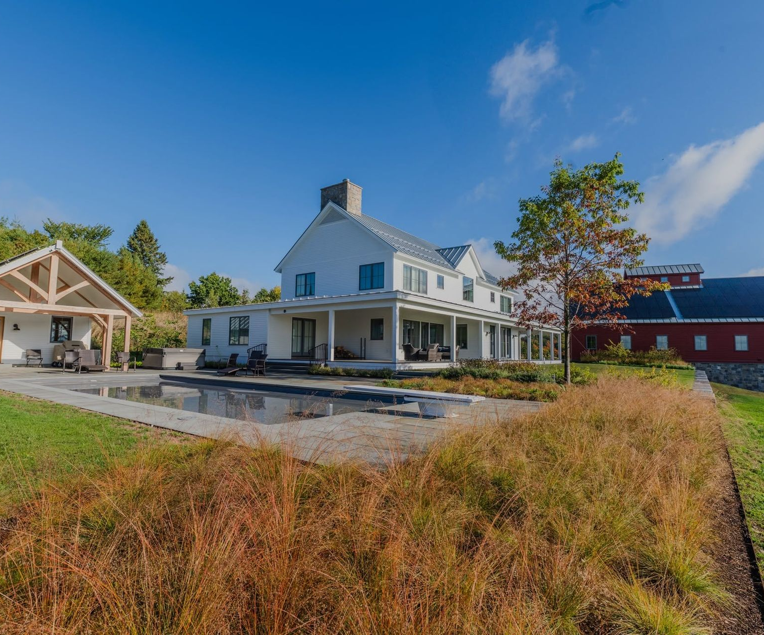 White house with porch beside a field of tall grass under a blue sky