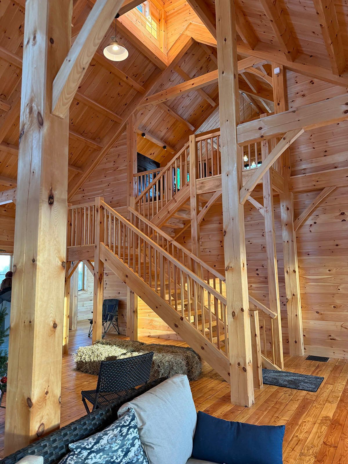 Rustic wooden cabin interior with staircase, exposed beams, and vaulted ceiling
