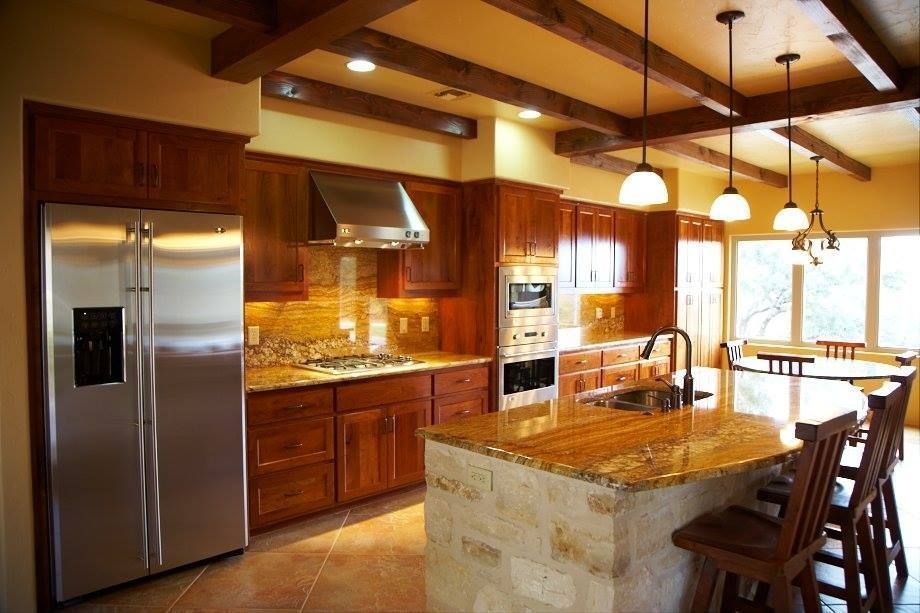 Modern kitchen with stainless steel appliances, wood cabinets, granite island, and bar stools