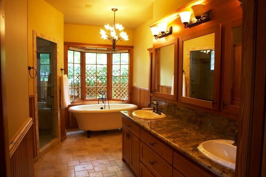 Warmly lit bathroom with a freestanding tub, double vanity, and large window