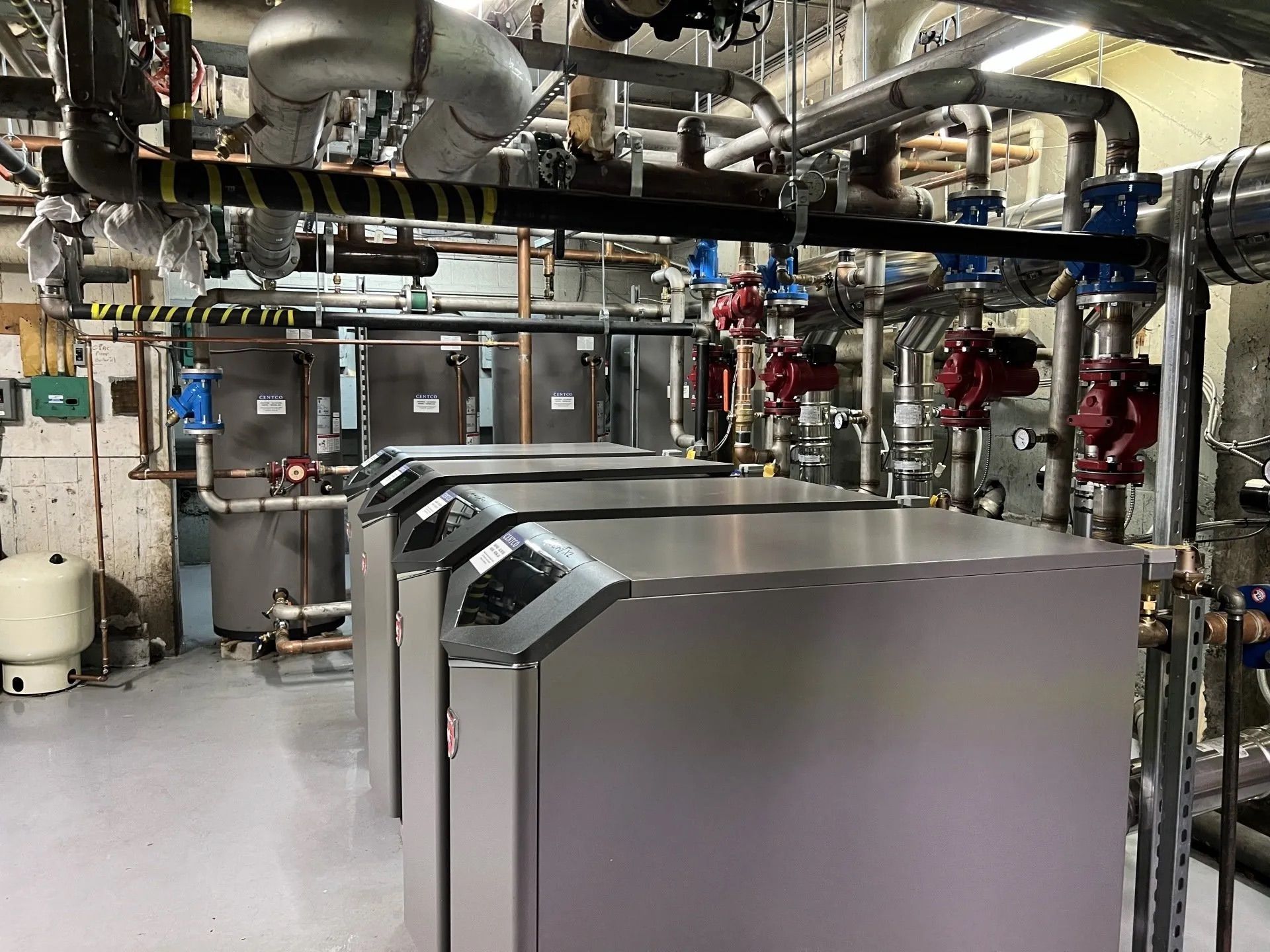 Local industriel avec équipements en acier inoxydable et tuyauterie aérienne dans une zone utilitaire propre