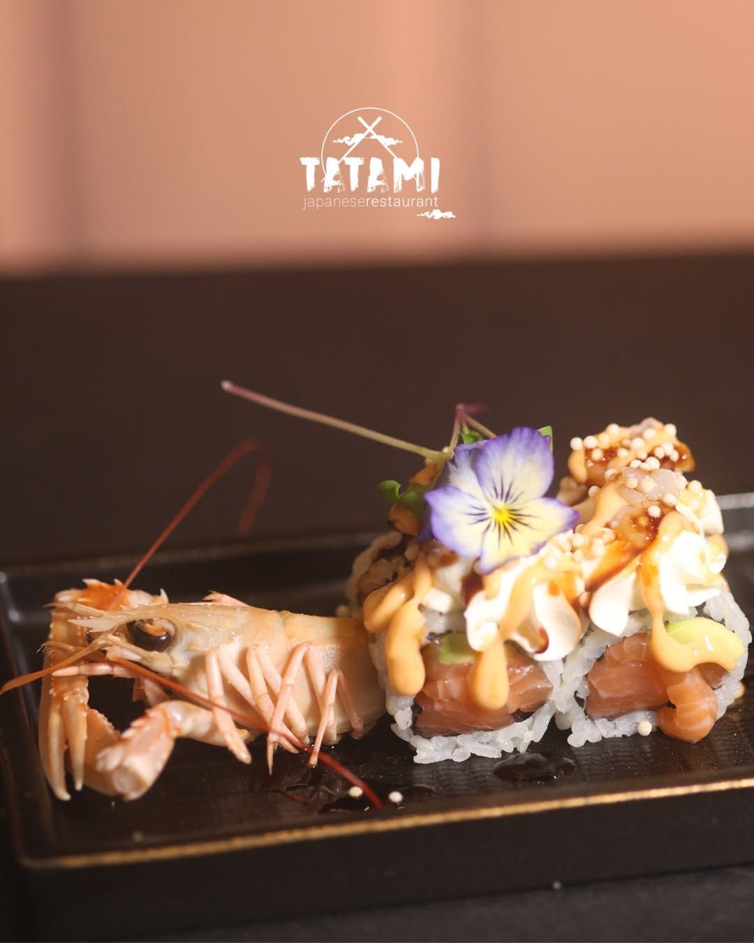Piatto di sushi con astice, involtini croccanti e fiori commestibili come guarnizione, servito su un piatto nero