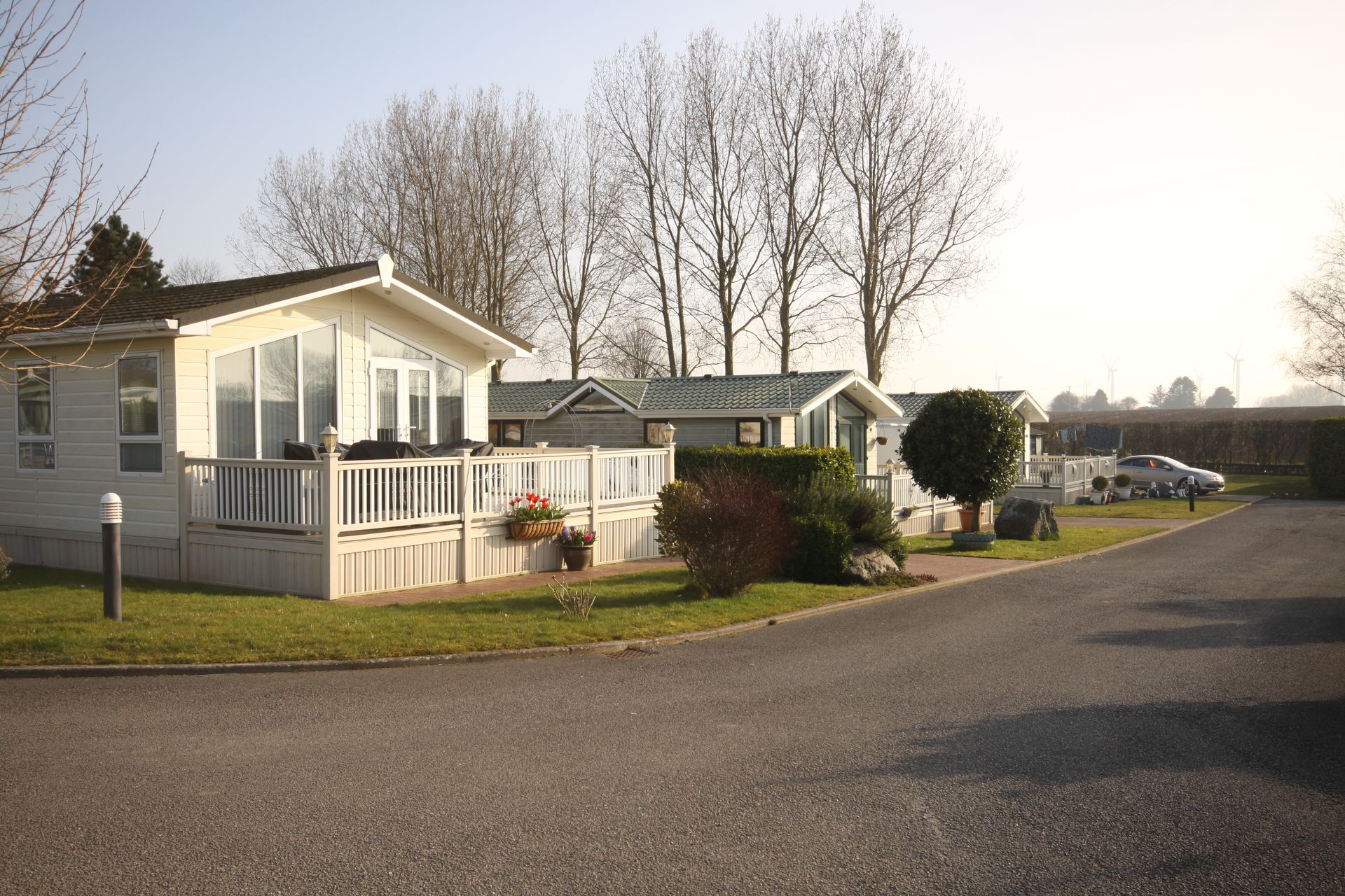 Static homes on a paved road, trees in background. Sunny day.