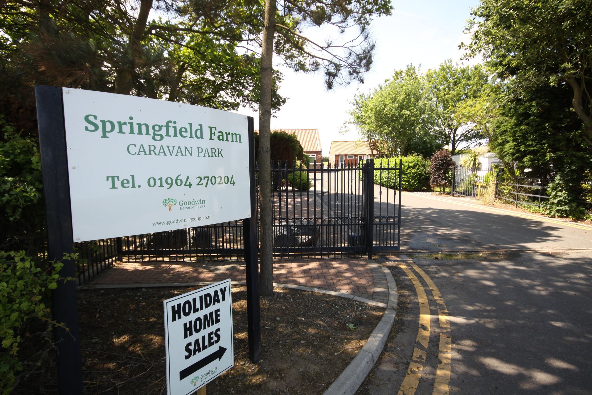 Sign for Springfield Farm Caravan Park with entrance gates; sunny day.