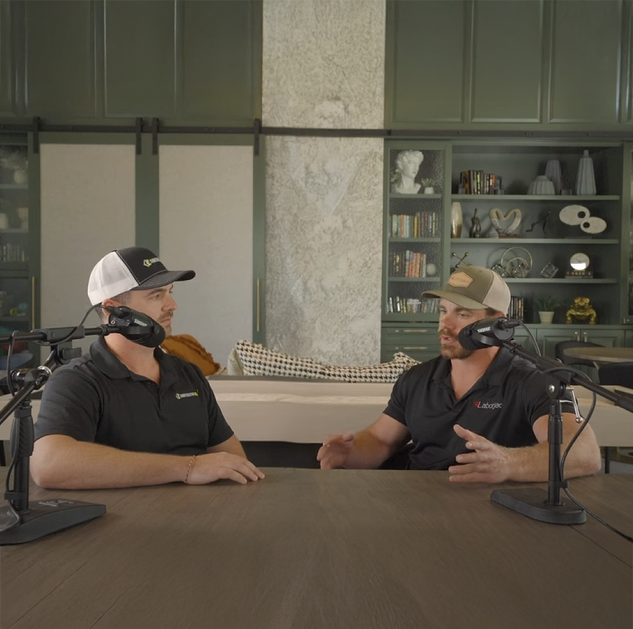 Two men are sitting at a table talking into microphones