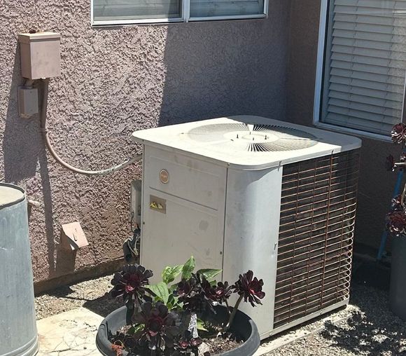 Two HVAC units, one new and enclosed, one old and open, outside a door.