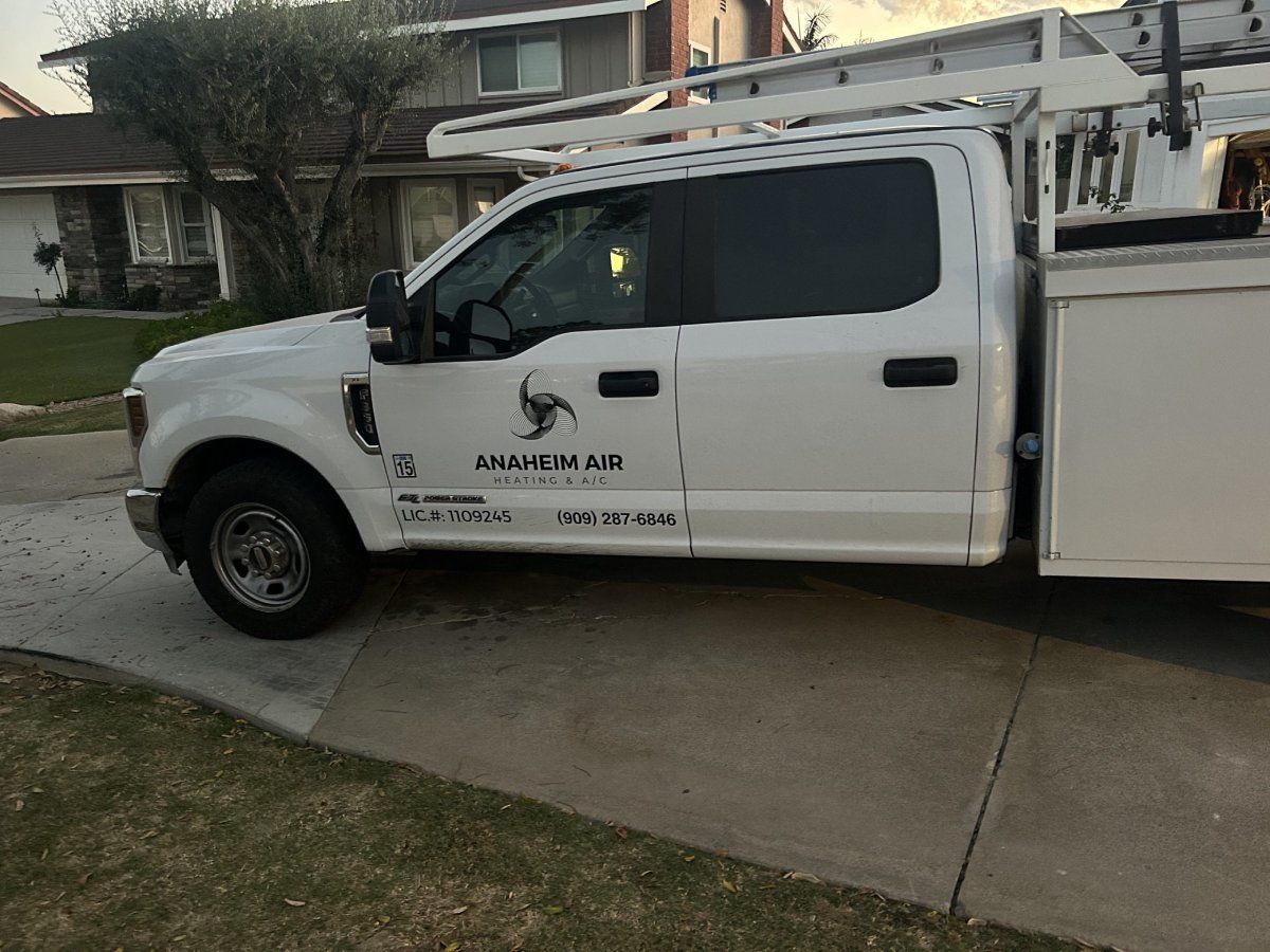 White work truck parked on a driveway with company logo and tools on the roof.