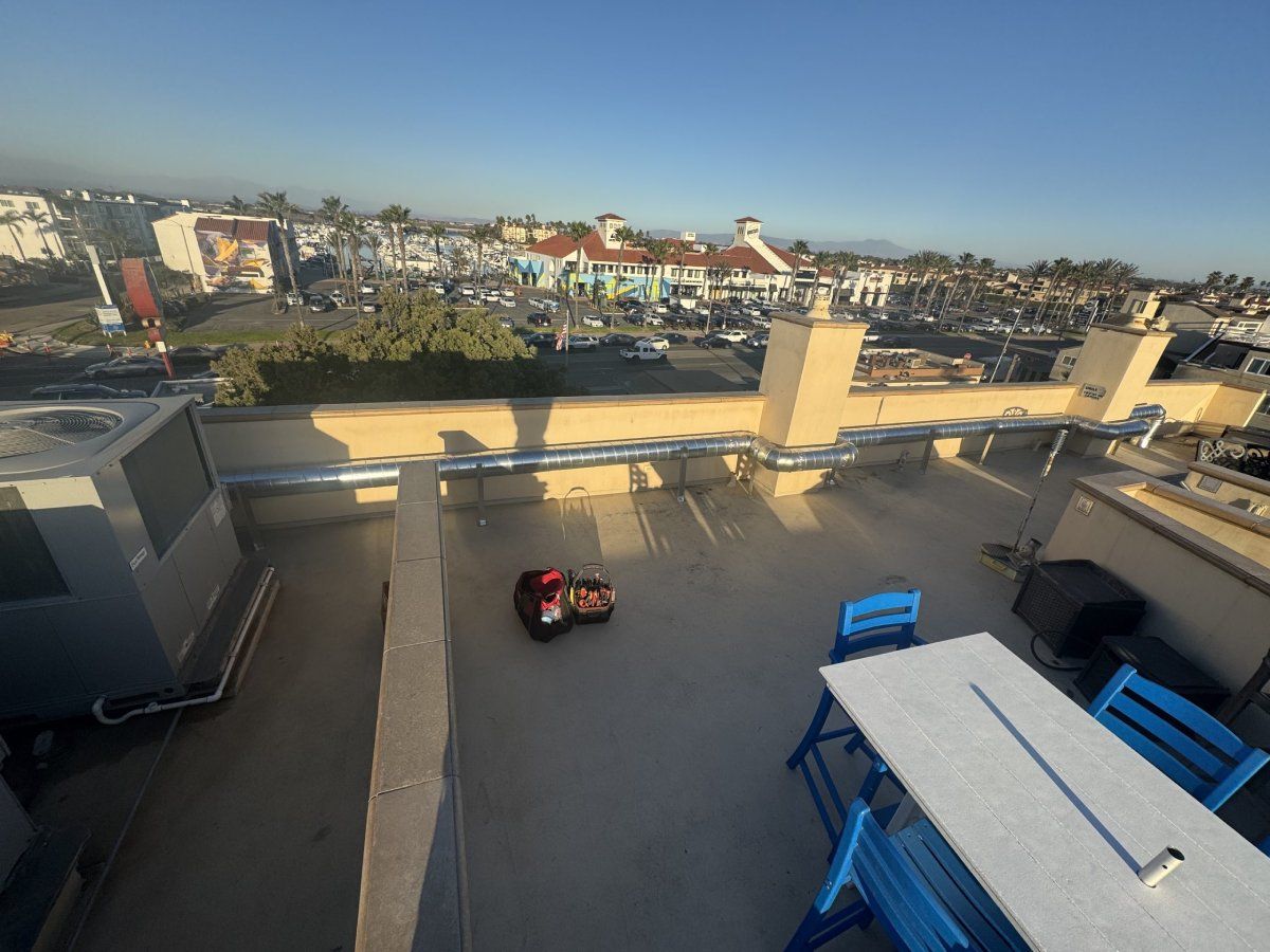 Rooftop with a lawnmower, blue furniture, and a city view on a sunny day.