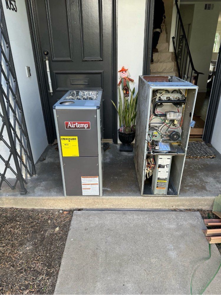 Two HVAC units, one new and enclosed, one old and open, outside a door.