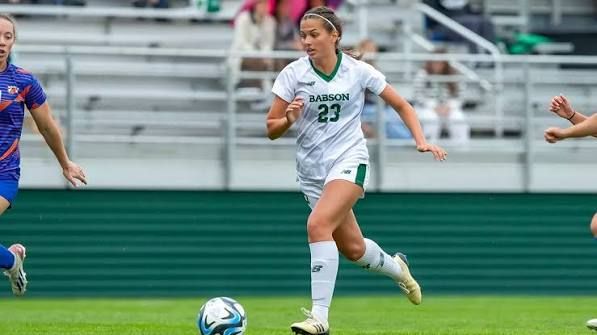 College soccer player dribbles the ball on a field